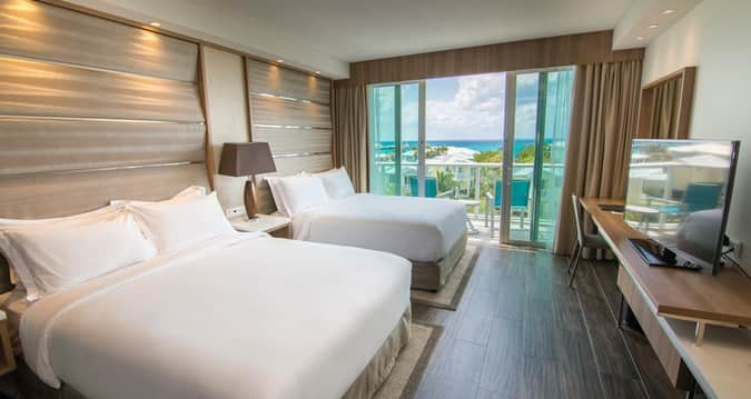 a room with two beds and a balcony overlooking the ocean