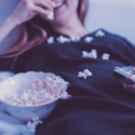 a woman lying down with popcorn on her chest