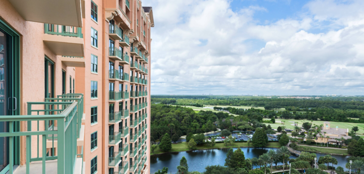 a high rise building with trees and a lake