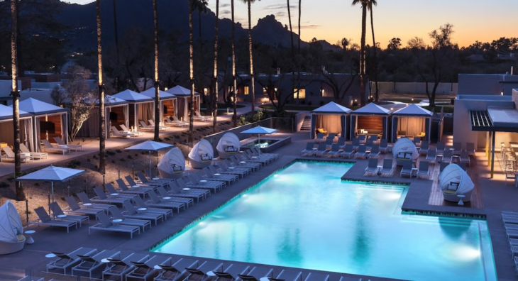 a pool with chairs and umbrellas in front of a resort