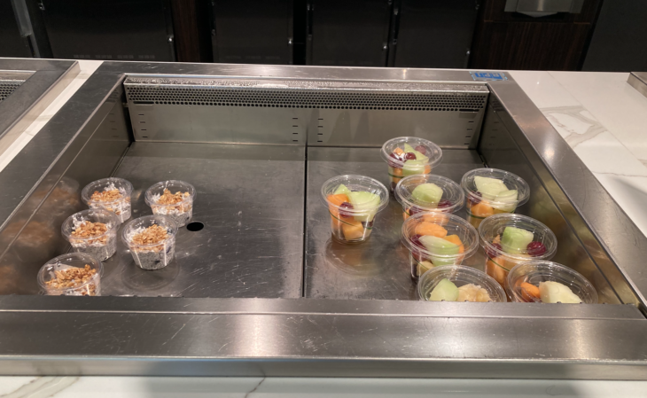 a counter with plastic cups of fruit and nuts