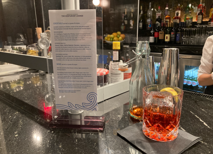a glass with a drink and a menu on a bar counter
