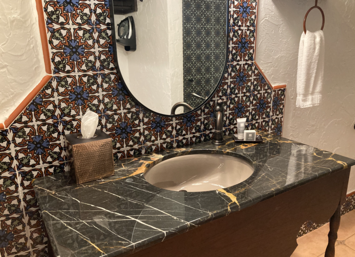 a bathroom sink with a mirror and a tile wall