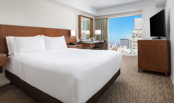 a hotel room with a large window and a large city view