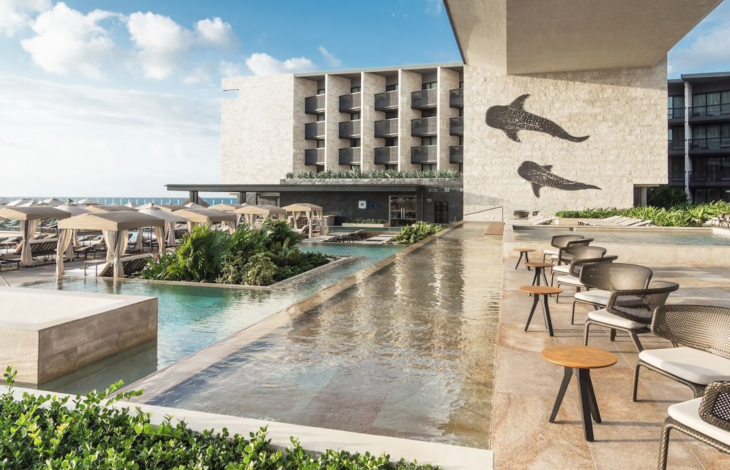 a pool with chairs and tables in front of a building