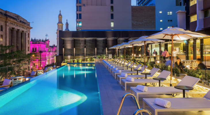 a pool with chairs and umbrellas on a rooftop