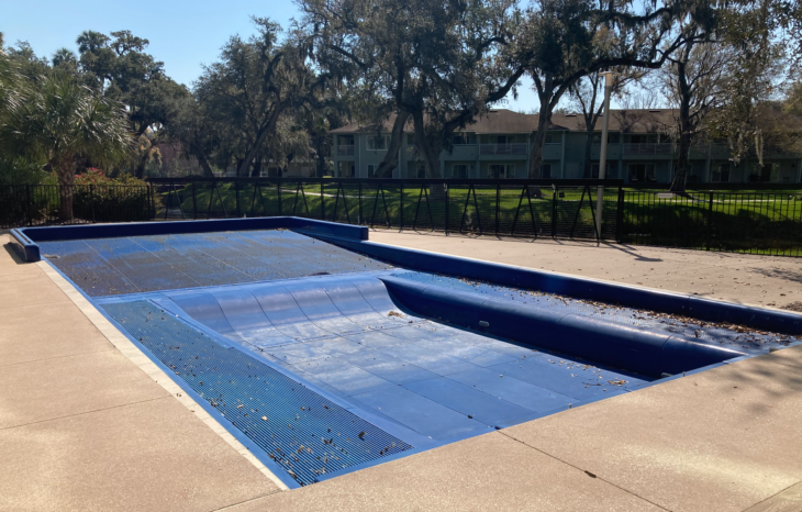 a pool with a fence and trees in the background