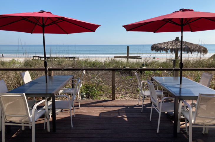 a table and chairs on a deck with umbrellas