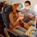 a man and woman sitting on an airplane drinking drinks