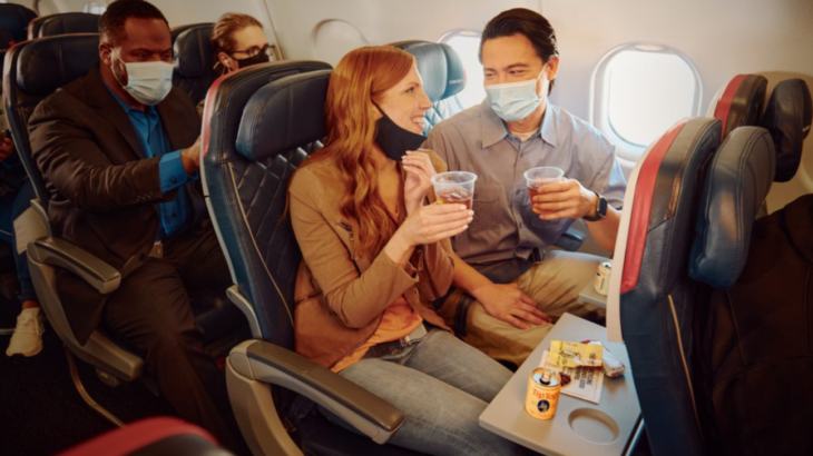 a man and woman sitting on an airplane with drinks