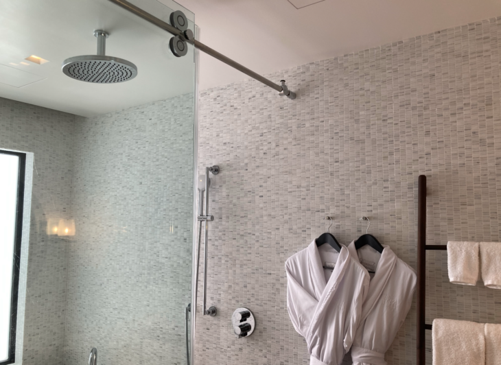 a shower with a white robe on a wall