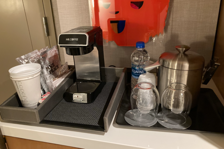 a coffee maker and cups on a tray