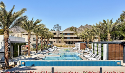 a pool with palm trees and a building in the background