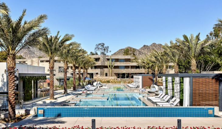 a pool with palm trees and a building