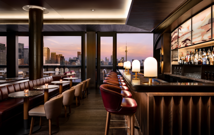 a bar with tables and chairs in a room with a view of a city