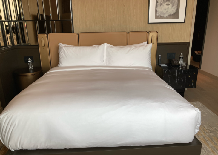 a bed with white sheets and a brown headboard