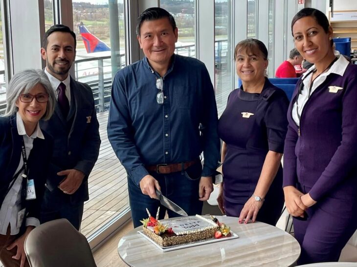 a group of people standing around a table with a cake