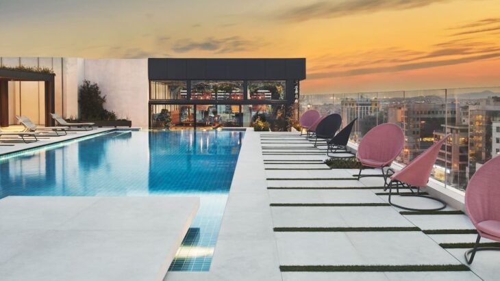 a pool with chairs and a building in the background