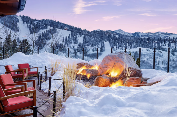 a fire pit with a snowy mountain and trees in the background